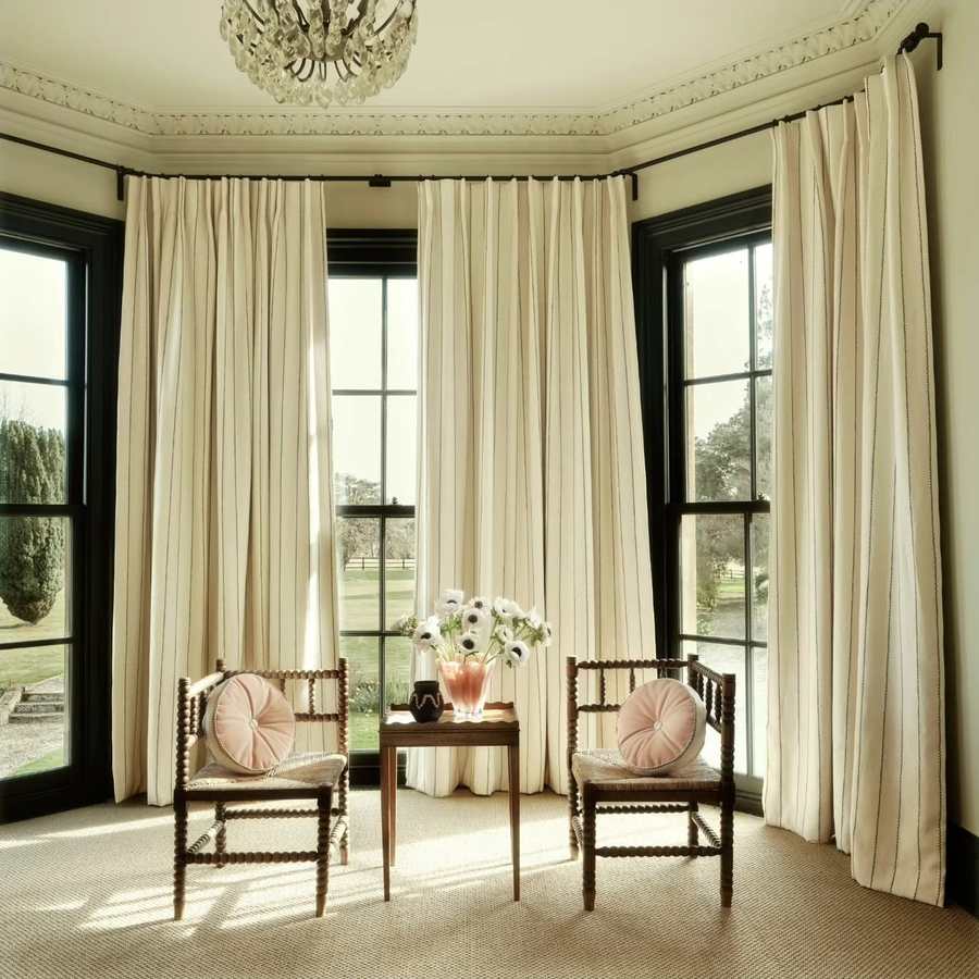 Cream curtains hung across a bay window