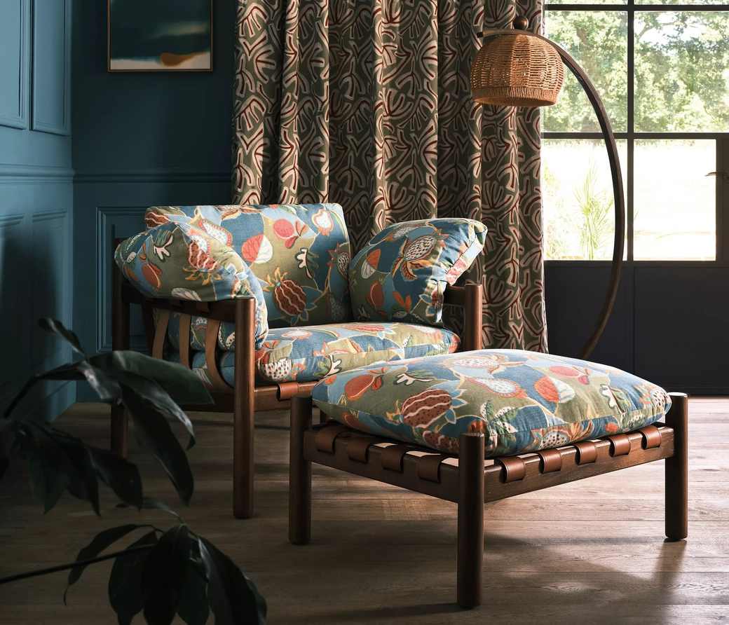 An armchair and full length curtains in a teal painted room
