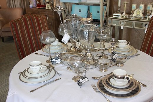 A dining table set with glassware and a place setting in the showroom