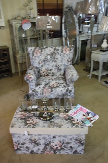 A floral upholstered armchair on the showroom floor beside a matching cushion