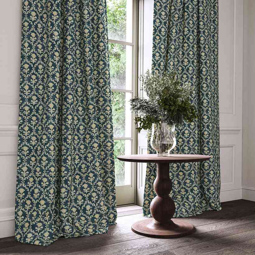 Green patterned curtains framing a window with the garden behind