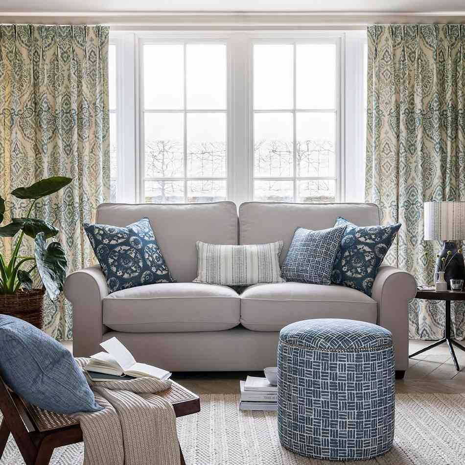 Full length curtains beside a sofa in a bright living room