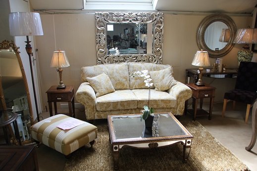 A living room setting on the showroom floor with a patterned sofa, cushions and a floor lamp